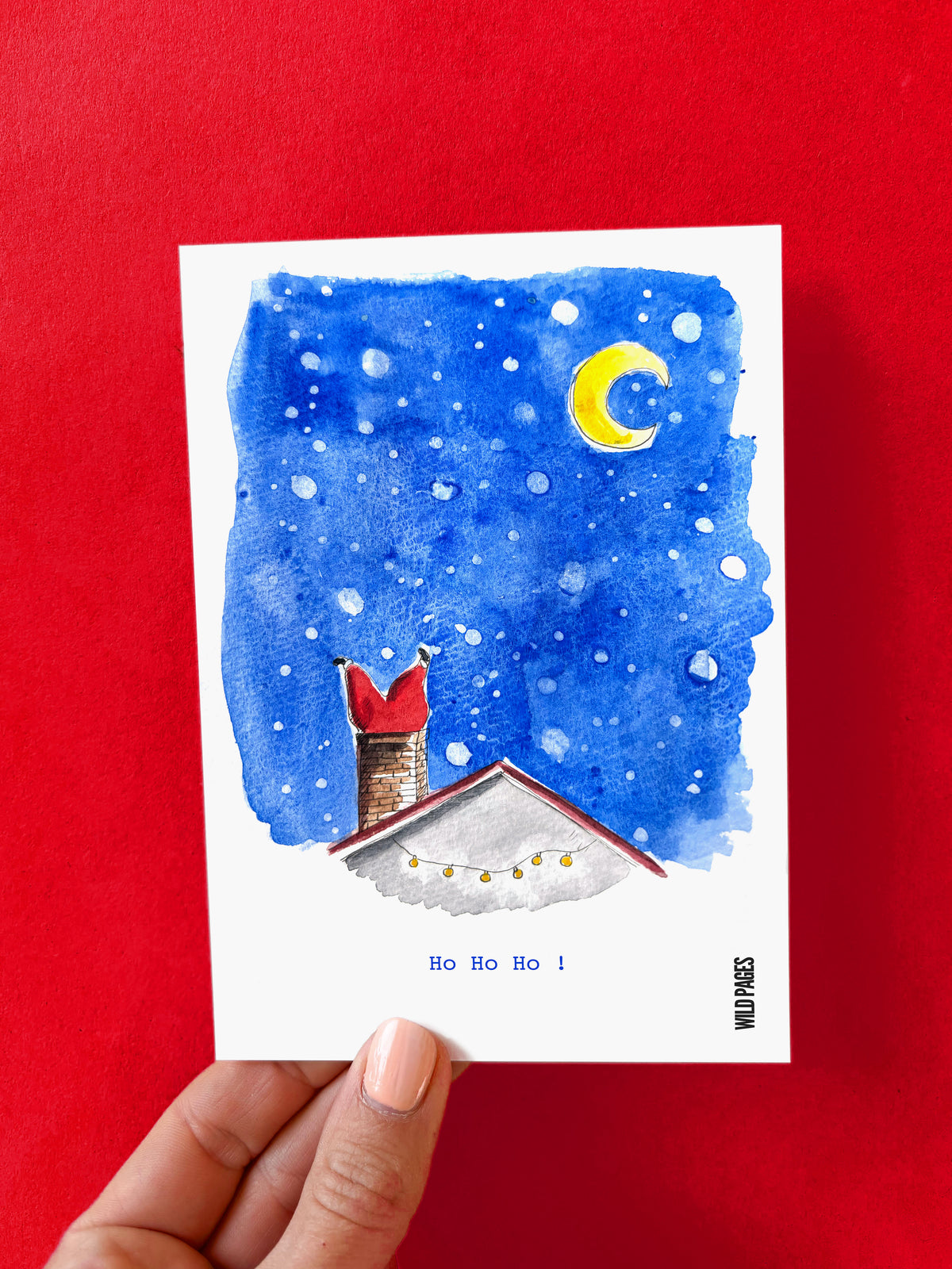 Illustration aquarelle d'un toit enneigé sous la lue, avec des bottes rouges dépassant de la cheminée, texte « Ho Ho Ho ! », carte tenue devant un fond rouge.